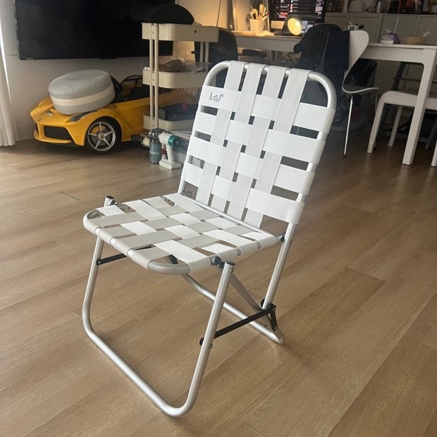A folding lawn chair photographed on a phone in a cluttered living room